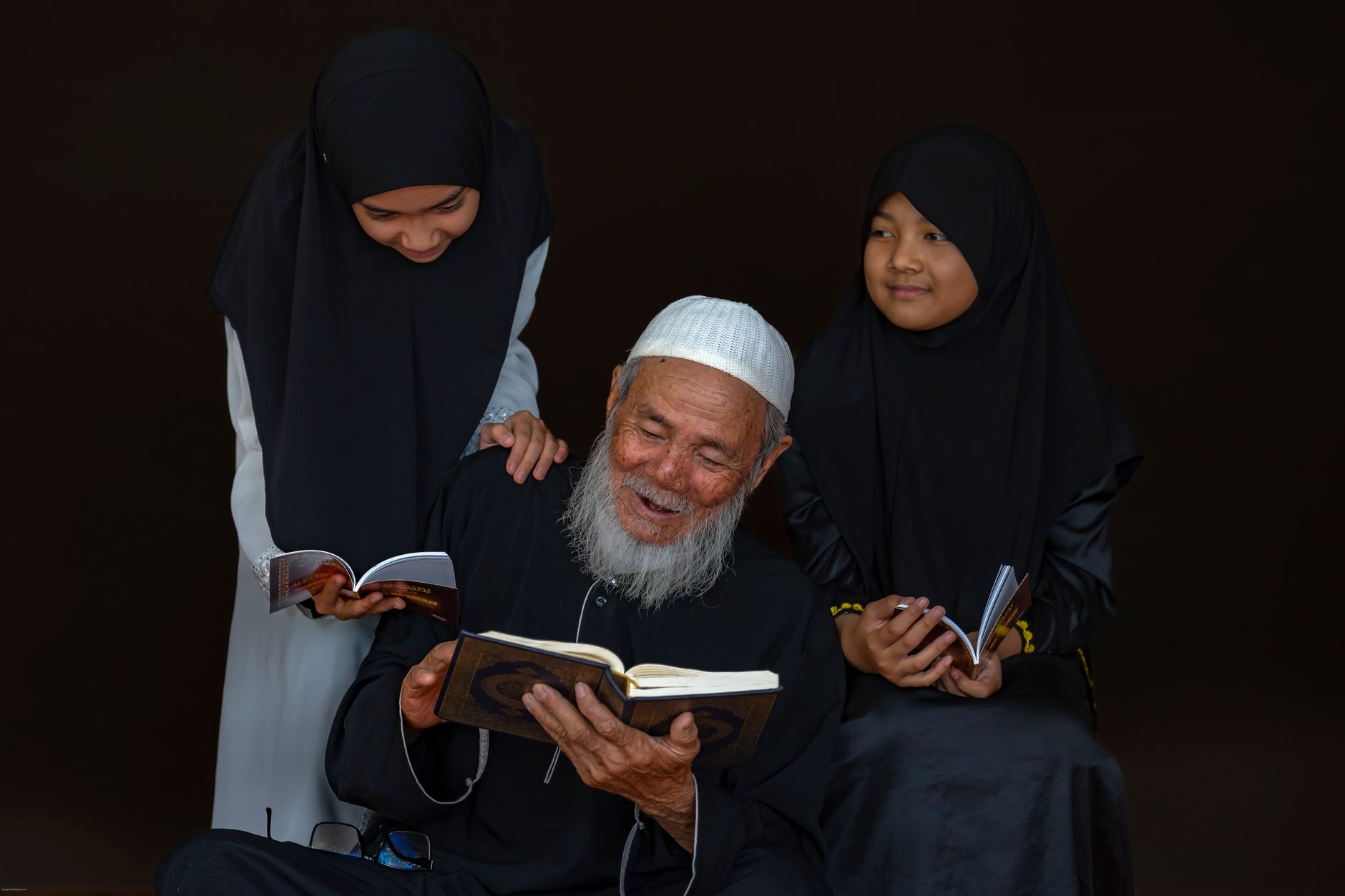 A father teaching his children about seeking knowledge in Islam at home in a modest setting.