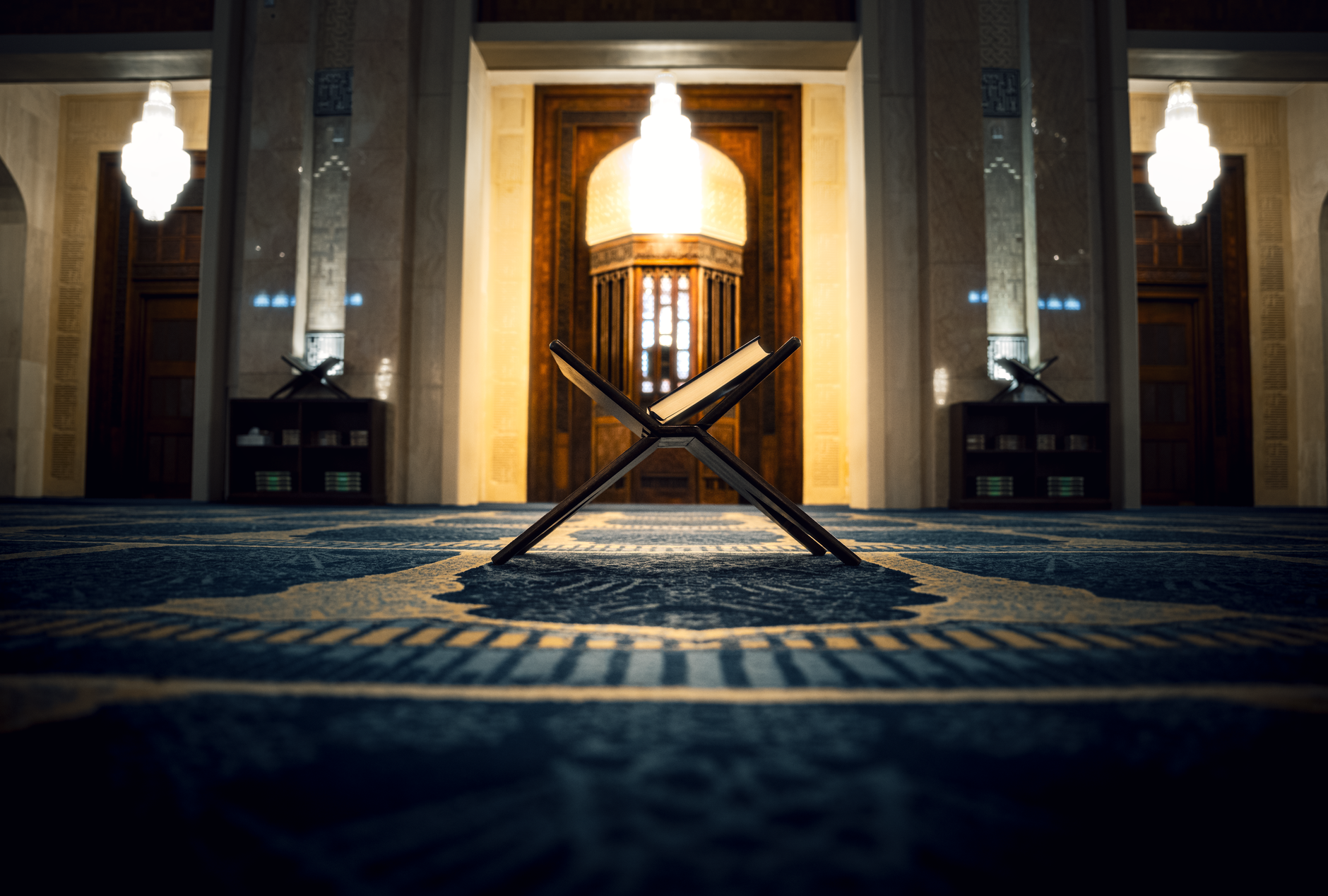 A Muslim man reflecting on the Quran while sitting in a quiet, traditional library.