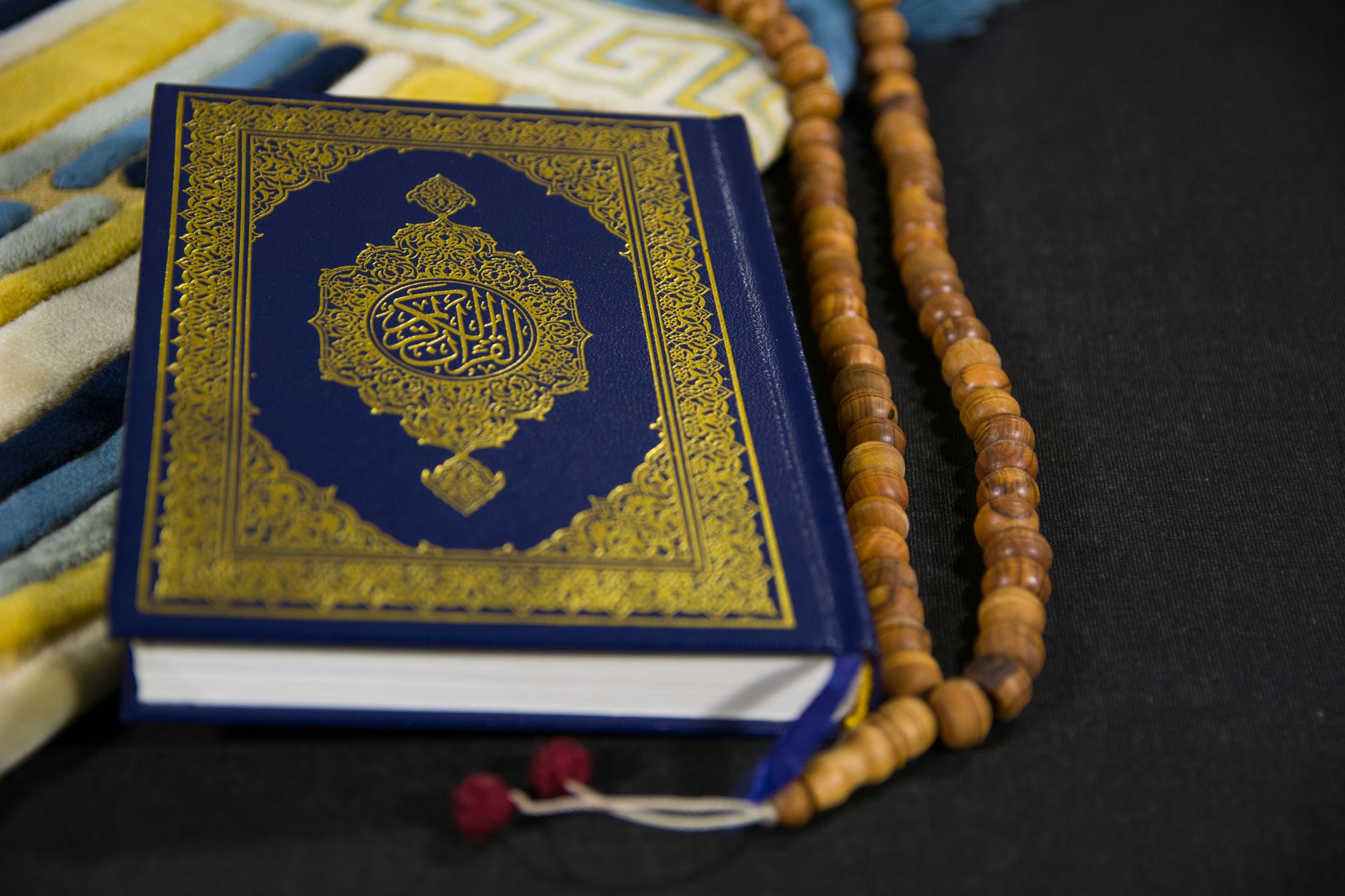 A Quran and prayer beads on a wooden stand during Itikaf in a mosque.